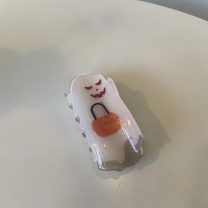 Detail view of a translucent white glitter ghost hair claw with a small orange pumpkin basket