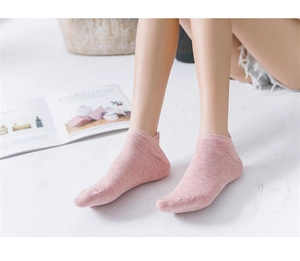 Close-up of pink breathable cotton low cut socks worn by model in cozy home setting