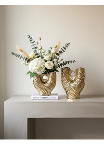 Détail de vases dorés en céramique avec texture martelée et design évidé élégant