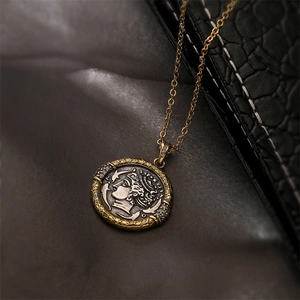 Gros plan du pendentif pièce vintage avec bordure dorée tissée et pierres noires