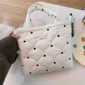 Detailed shot of white quilted tote bag with black polka dots and a fabric label