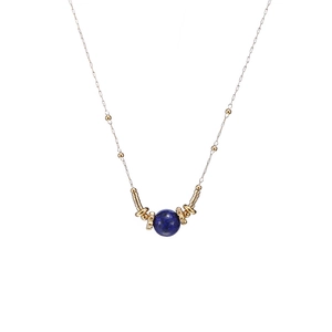 Detailed close-up of a blue lapis lazuli pendant with gold cylindrical accents on a chain