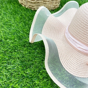 Détails d'un chapeau de paille avec ruban de cœurs brodés et bordure en mesh ondulé