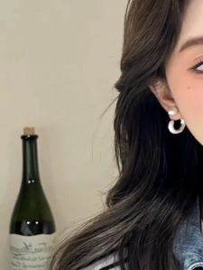Detailed view of silver C-shape earrings with pearls worn by a model in a modern style