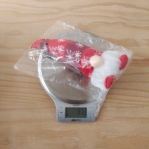 Detailed view of weighted Christmas gnome decoration with snowflake knit hat in plastic bag