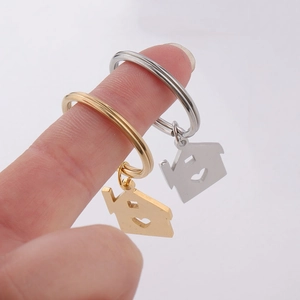 Detail of house-shaped keychains with heart cutouts in polished gold and silver finishes