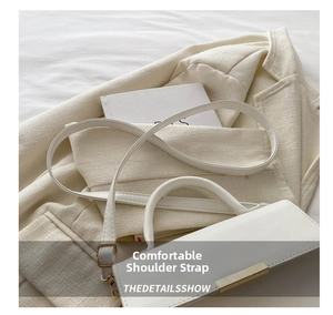 Detail of the soft white leather strap and gold buckle on a minimalist small handbag