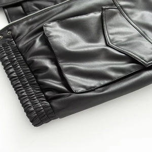Close-up of black leather jacket with elastic hem, flap pockets and metal zipper detail