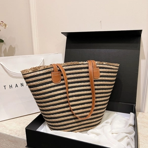 Macro detail of natural straw woven tote bag with black stripes and brown leather handles