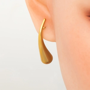 Close-up of elegant gold hollow spiral drop earrings worn on ear with minimalist design