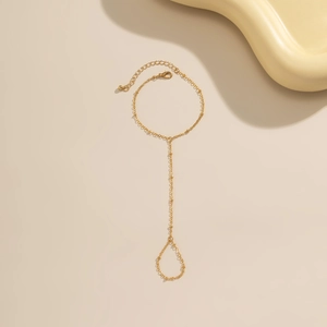 Macro shot of minimalist gold link hand chain with faux pearl and rhinestone accents