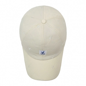 Quilted cream baseball cap featuring blue bird embroidery and minimalist design