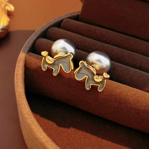 Detail of 18K gold plated horse stud earrings with large grey pearls on velvet