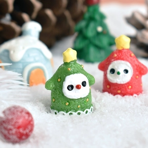 Miniature resin Christmas figurines featuring snowman and tree on artificial snow background