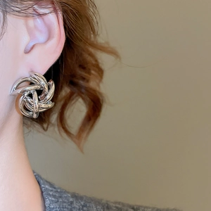 Close-up of silver interwoven spiral knot stud earrings worn by a model