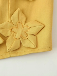 Détail macro de la décoration florale 3D jaune sur un tissu en sergé de haute qualité