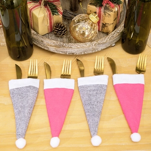 Nahaufnahme von rosa und grauen Filz-Weihnachtsmützen als Besteckhalter mit Gabeln
