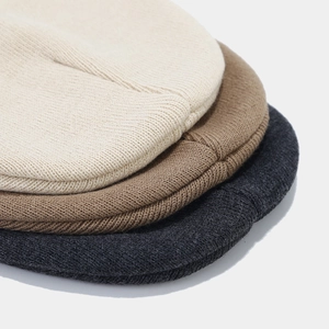 Macro detail of soft knit texture on beige, khaki, and dark grey winter beanies