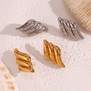 Detailed view of layered wing stud earrings in gold and silver with shell texture