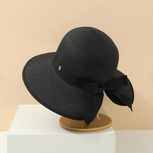 French style black straw sun hat with ribbon bow and gold metal buckle on a stand