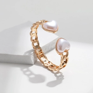 Detail of gold-plated chunky chain bracelet featuring dual white pearl heart accents