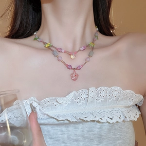 Close-up of double-layer beaded necklace with pink glass flower and teardrop pendants