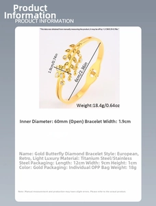 Detail view of gold titanium steel open cuff bangle with butterfly and leaf charms