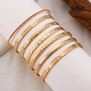Set of 8 gold boho bangles with arrow star and geometric patterns on white display