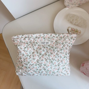 Trousse à maquillage matelassée à fleurs roses avec étiquette sur un fond esthétique blanc