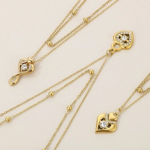 Close-up of golden heart pendant with inset crystals and bead chain necklace details