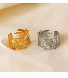 Close-up of golden and silver feather-textured rings on soft silk fabric