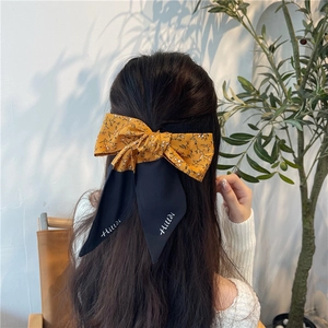 Dettaglio di un fermaglio per capelli a fiocco floreale nero con nastri lunghi