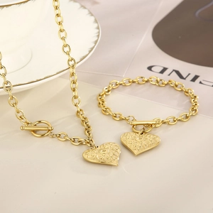 Detailed view of golden heart pendant necklace and bracelet set with T-bar toggle clasp