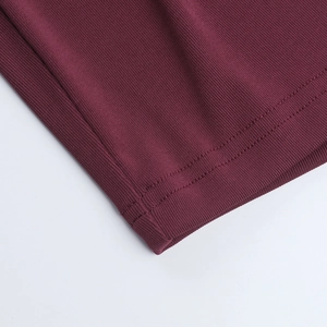 Macro detail of wine red ribbed knit fabric and neat hemline stitching on the dress
