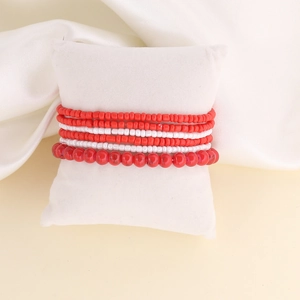 Detail of red and white multi-layer beaded bracelet set on a white display pillow