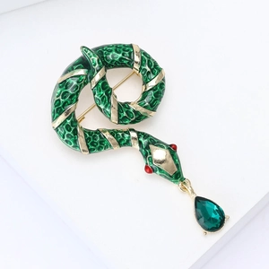 Close-up of green enamel snake brooch with gold plating and teardrop crystal pendant
