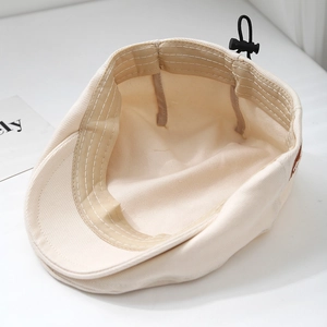 Inside view of beige cotton beret with adjustable buckle and elastic strap for kids