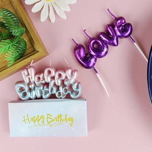Macro shot of gradient glitter Happy Birthday and LOVE letter candles with gift box