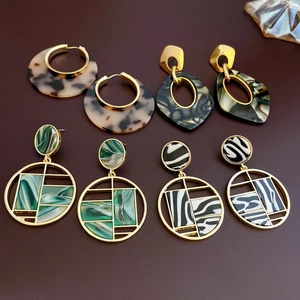 Vue à plat de boucles d'oreilles géométriques en résine ambre, marbre vert et zèbre