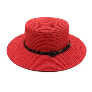 Detail of red straw flat top sun hat featuring black woven rope and metal fastener