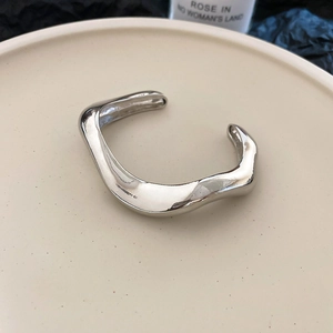 Macro shot of silver wave-shaped adjustable bangle with high-polished mirror finish