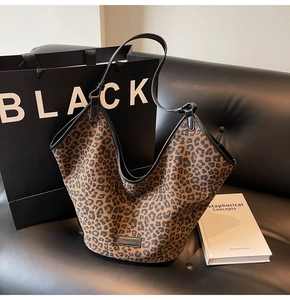 Detail of leopard print tote bag with black leather handle on a dark sofa