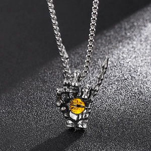 Macro detail of gothic skull hand pendant with tiger eye stone on a vintage chain