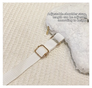 Detail of adjustable strap and golden buckle on white plush cloud crossbody bag