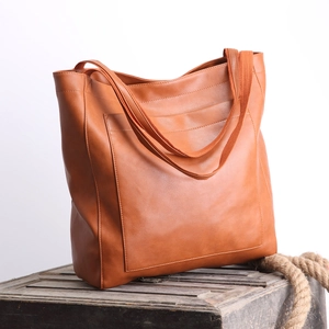 Détail du sac cabas vintage en cuir marron sur une caisse en bois avec corde de chanvre