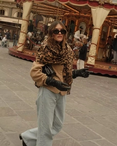 Detail of leopard print scarf paired with black leather gloves and khaki jacket