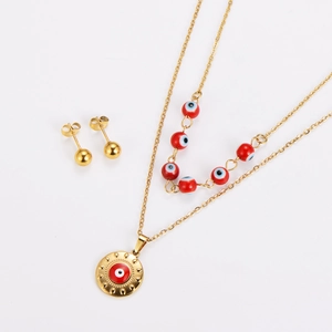 Détail de la parure Evil Eye dorée avec collier double couche et perles rouges chic