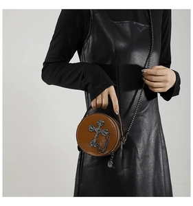 Close-up of a brown gothic round crossbody bag with metal cross and chain detailing