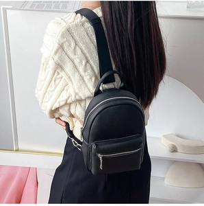 Detail of black pebbled leather mini backpack with silver metal zippers and pocket
