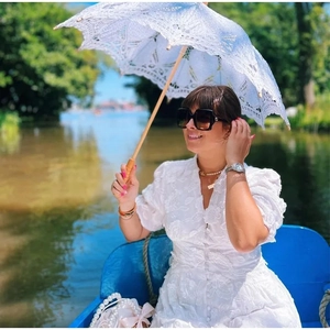 Détail d'un mannequin en robe de dentelle blanche avec ombrelle sur un bateau